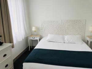 um quarto com uma cama branca, 2 mesas de cabeceira e uma janela em Sea View em Saint-Gilles-Croix-de-Vie