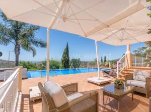 een villa met een zwembad en een patio met parasols bij Casa Mocho Branco in Loulé