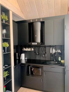 una cocina con encimera negra y fregadero en HARMONY Design and Vacation House en Bigauņciems