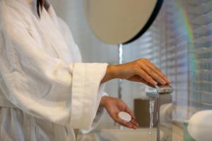 a woman in a white towel is washing her hands at Marpessa Hotel & Spa in Agrinion