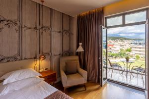a bedroom with a bed and a chair and a balcony at Marpessa Hotel & Spa in Agrinion