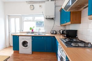 a kitchen with blue cabinets and a washing machine at Chic 3 Bed House for up to 6 people in the city of Manchester in Manchester