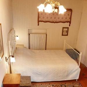 um quarto com uma cama branca e um lustre em Gîte de Rangère em Villapourçon