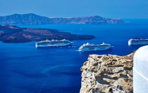 three cruise ships in a large body of water at Volcano View by Caldera Collection in Fira