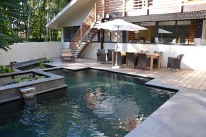 a swimming pool with a table and chairs and an umbrella at B&B Wepa-hof in Oud-Turnhout