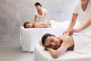 a woman getting a massage from two men in beds at HAIDVOGL MAVIDA Zell am See in Zell am See