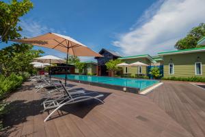 a swimming pool with lounge chairs and an umbrella at Sky Hip Resort - SHA Certified in Jomtien Beach