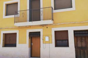 a yellow building with a balcony and two doors at Casa con terraza/Confortable house with terrace in Aigues
