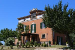 ein großes orangefarbenes Haus mit grünen Fensterläden und einem Baum in der Unterkunft DIMORA MARELLA Patrica - Frosinone in Patrica