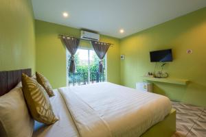 a bedroom with a bed and a window with a television at Sky Hip Resort - SHA Certified in Jomtien Beach