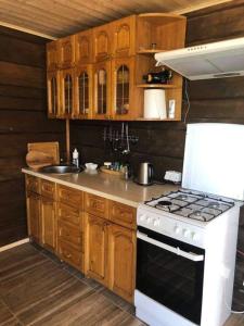 a kitchen with wooden cabinets and a white stove top oven at Pas Garfildą in Vatušiai