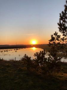 een zonsondergang boven een waterlichaam met zonsondergang bij Pas Garfildą in Vatušiai