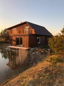 eine Holzhütte neben einem Wasserkörper in der Unterkunft Pas Garfildą in Vatušiai