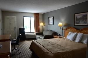 a hotel room with a bed and a chair at Clarksville Inn in Clarksville