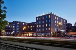 ein Gebäude in der Nacht mit einer Eisenbahnstrecke davor in der Unterkunft Me and All Hotel Kiel, by Hyatt in Kiel