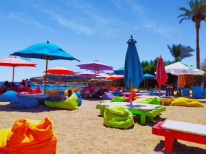 a beach with umbrellas and people sitting on the sand at Naama Blue Hotel in Sharm El Sheikh