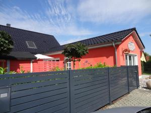 a red house with a black fence in front of it at Ferienhaus Loissin in Loissin