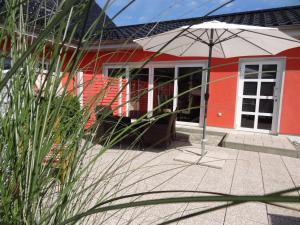 a red house with an umbrella in front of it at Ferienhaus Loissin in Loissin +11 photos