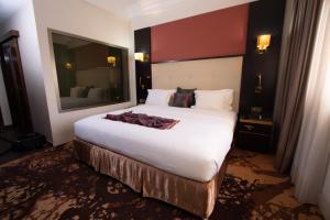 a bedroom with a large white bed with a large mirror at Hôtel Fleur de Lys Plateau in Dakar