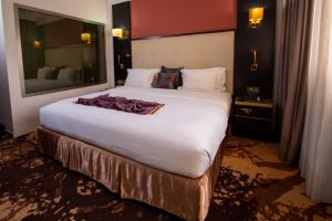 una camera da letto con un grande letto bianco e un grande specchio di Hôtel Fleur de Lys Plateau a Dakar