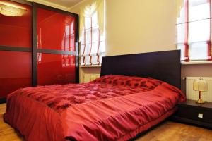 Cama roja en habitación con ventanas en Raina Lux Apartment, en Riga