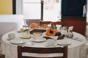 una mesa con un mantel blanco con comida. en Pousada Beira Mar, en Garopaba