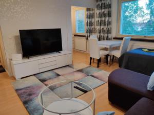 een woonkamer met een televisie en een tafel met stoelen bij M Apartments Vuorentaustantie in Tampere