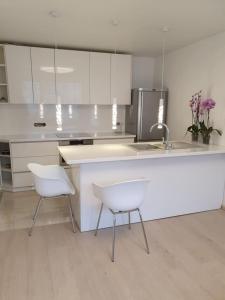 a white kitchen with two white chairs and a counter at Home sweet home in Radviliškis