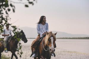 Una mujer montando un caballo junto a un hombre en Hotel Erodios, en Lithótopos