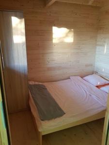Cette petite chambre comprend un lit dans une cabane en bois. dans l'établissement Domki w sadzie Stegna, à Stegna