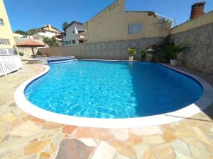 a large swimming pool in a yard with a stone patio at Hotel Pousada Miami in Itanhaém