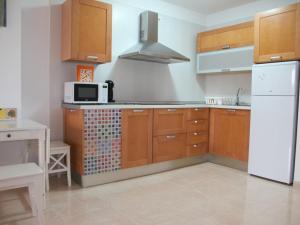 een keuken met houten kasten en een witte koelkast bij Apartmento La Perla el Medano in El Médano