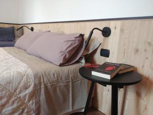 a bed with a table with a lamp and a book at B&B Mirò in Pieve di Soligo