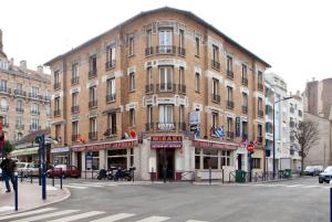duży ceglany budynek na rogu ulicy w obiekcie Hotel Victor Hugo w mieście Clamart