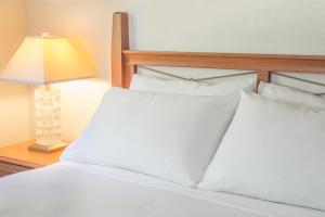 a bed with white sheets and a lamp on a table at Robin Hood Inn and Suites in Victoria