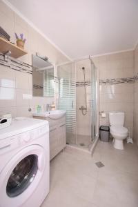 een witte badkamer met een wasmachine bij Happy Days Home Apartment und Studio/Penthouse in Ialyssos