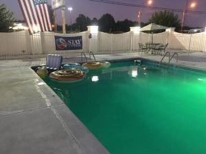 una piscina con agua verde en un patio en Stay Express Inn & Suites Demopolis, en Demopolis