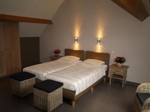 a bedroom with a large bed with two chairs and lights at De Jölenberg in Heers