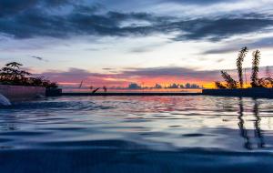 un bassin d'eau avec un coucher de soleil en arrière-plan dans l'établissement Casa Unicornio Azul, à Uvita