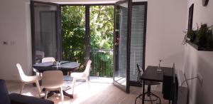 a living room with a table and chairs and a balcony at Piacsek Apartmanház in Pécs