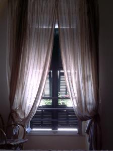 una ventana con cortinas blancas en un dormitorio en La Torre, en Isolabona