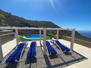 un grupo de sillones azules en un balcón con piscina en Apartamentos colon y bungalows, en Los Quemados
