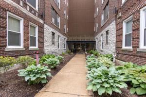a sidewalk in front of a brick building with plants at Vibrant Pad next to ForestPark/BJC/WashU in Maryland Heights