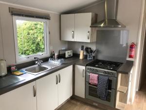 a kitchen with a stove and a sink and a window at Luxury 3 Bedroom Caravan MC37, Shanklin, Isle of Wight in Shanklin