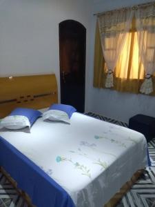 1 dormitorio con 1 cama blanca grande con sábanas azules en Pousada Guarulhos, en Guarulhos