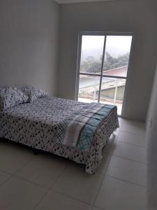 een slaapkamer met een bed en een groot raam bij Apartamento em Guaramiranga in Guaramiranga