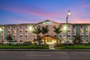 un gran hotel con coches estacionados frente a él en WoodSpring Suites Naples West en Naples