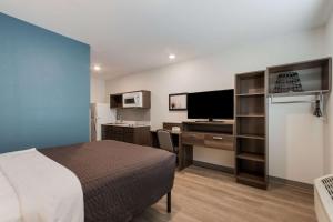 Habitación de hotel con cama y escritorio con TV. en WoodSpring Suites Tamarac, en Tamarac