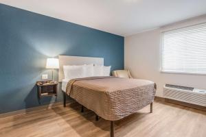 ein Schlafzimmer mit einem Bett und einer blauen Wand in der Unterkunft WoodSpring Suites Doral Miami Airport in Miami