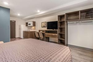 a bedroom with a bed and a desk and a kitchen at WoodSpring Suites Doral Miami Airport in Miami
